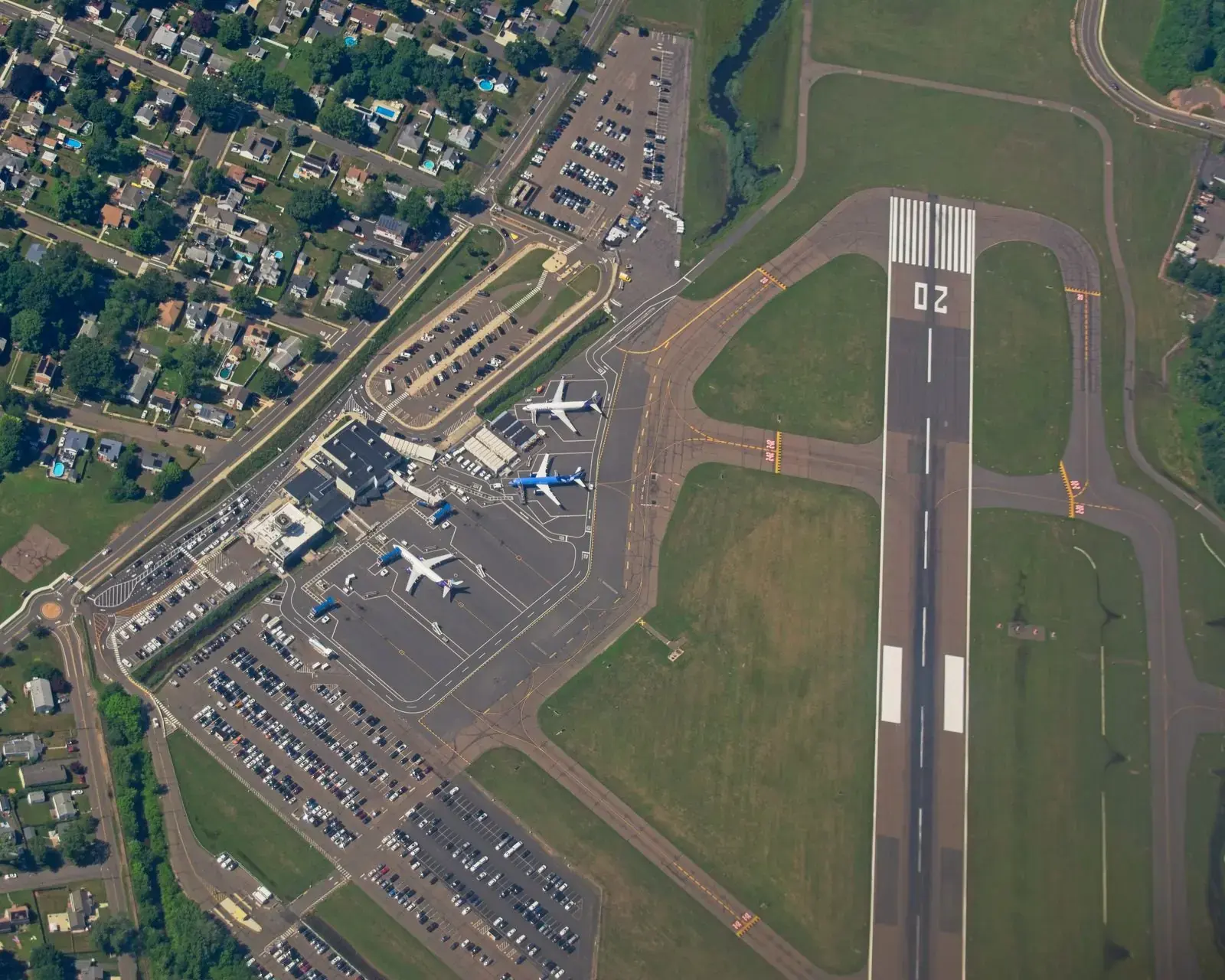 Aerial photograph of a runway, taxiways, a terminal, and airliners parked at the gates